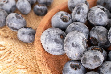 A few juicy blueberries in a wooden plate on a jute napkin, macro.