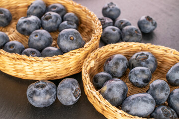 A few juicy blueberries in straw plates on a slate stone. macro.