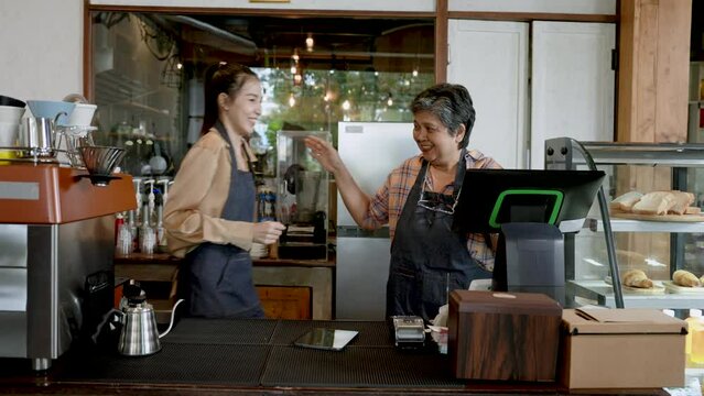 Asian female senior single mom Called my daughter to look at the online cash register, lots of drink orders coming in, beautiful Asian baristas. owner's daughter is happy and hugs her mother happily.
