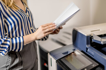 Photocopying documents at work. A young woman uses a photocopier.