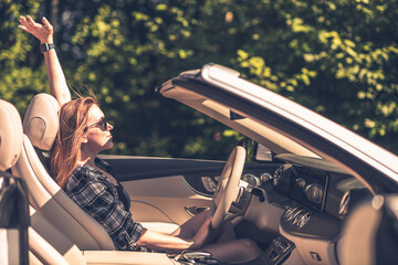 Young happy business woman in a plaid shirt driving a convertible. - 630826934