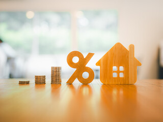 Percentage and house symbol with coins stack on wood table. Concepts of home interest, real estate,...