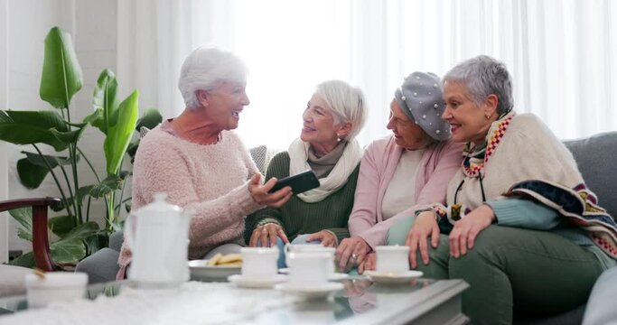 Phone, social media and senior woman friends in the living room of a home together for a tea party. Smile, retirement and a group of elderly people sitting on a sofa together while laughing at a meme