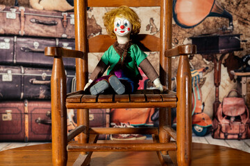 Obraz na płótnie Canvas vintage clown doll sitting on old children's wooden rocking chair in attic