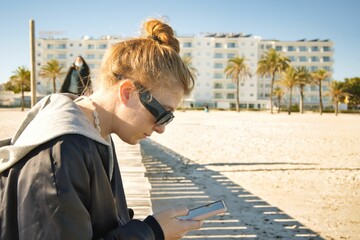 mirando el móvil en la playa