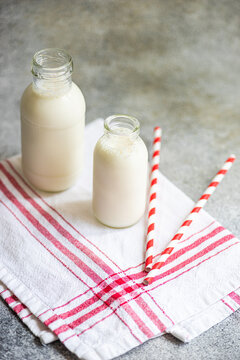 Raw cow milk in vintage bottles on rustic napkin and drinking straws