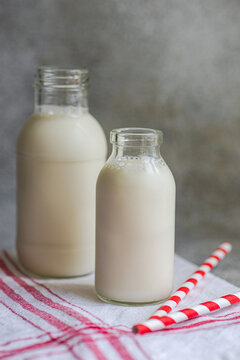 Raw cow milk in vintage bottles on rustic napkin and drinking straws