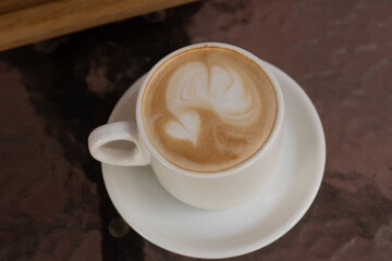 the white ceramic cup of americano with milk on the glass coffee table. Morning coffee