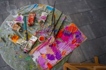 close-up of paint palettes with traces of oil paint on them and a brush lying next to them in the...