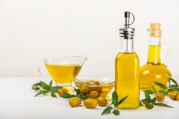 Olive oil in a bottle and gravy boat on the kitchen table. Oil bottle with branches and fruits of olives. Place for text. copy space. vegetable oil and salad dressing.