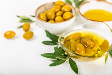 Olive oil in a bottle and gravy boat on the kitchen table. Oil bottle with branches and fruits of olives. Place for text. copy space. vegetable oil and salad dressing.