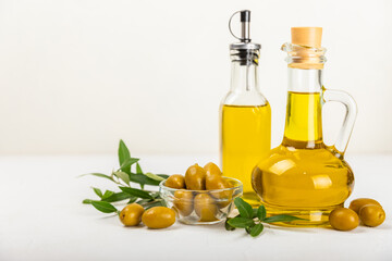 Olive oil in a bottle and gravy boat on the kitchen table. Oil bottle with branches and fruits of olives. Place for text. copy space. vegetable oil and salad dressing.