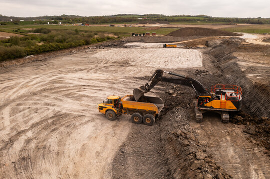 Aerial view above a digger loading a dumper truck on a brownfield site in the construction industry