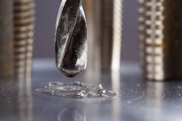 metal drill bit with lubrication oil liquid make holes in steel billet on industrial drilling...