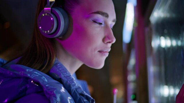 Woman looking snacks vending machine late evening close up. Girl in headphones.