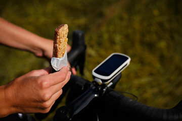 Cycling snack.Sports snack for cyclist.A sports bar in the hand of a cyclist against the background...