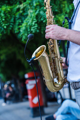 Jazz musician artist playing saxophone in the street of a European city. A street musician plays...