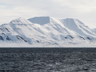 Landscape of Arctic Ocean with shore, hills, snow and sea, Spitsbergen
