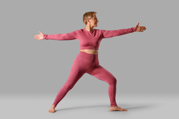 Fototapeta premium Sporty mature woman practicing yoga on grey background