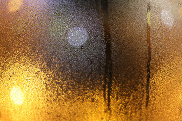 Soft focus blur water rain drops on wet window glass with city lights.