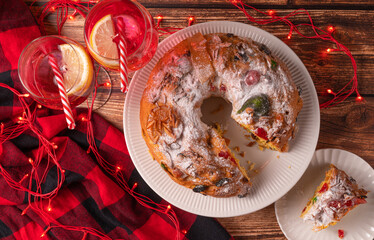 Portuguese Bolo Rei is a traditional Chrismas cake with fruits and icing on wooden table. Flat lay