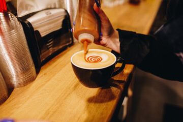 Barista pouring caramel on a coffee