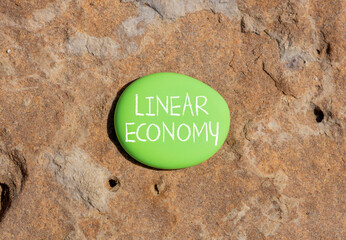Linear economy symbol. Concept words Linear economy on beautiful green stone. Beautiful brown stone...