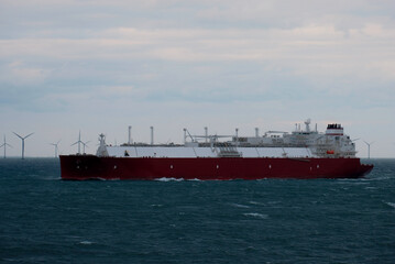 A very large gas carrier is underway with a wind park in the background. LNG tanker. Fully loaded gas tanker.