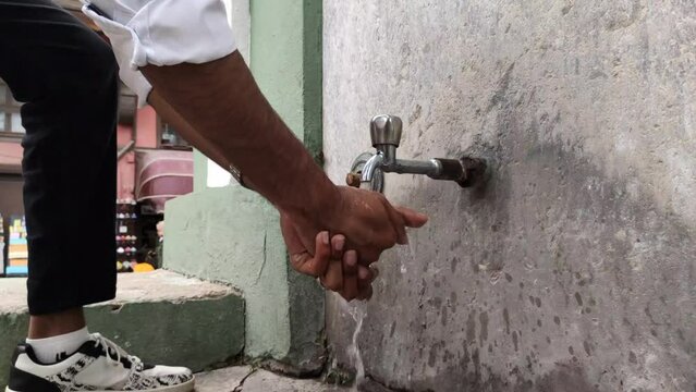 a man washes his hands at a public water faucet on the street, a public water faucet in a city in Turkey that is clean and can be used for washing hands and can be drink
