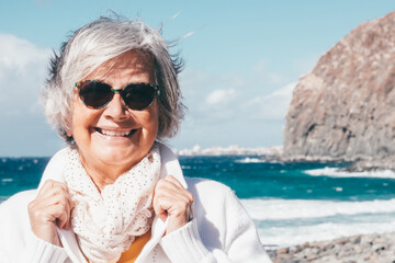 Portrait of happy senior white-haired woman in outdoors enjoying sea vacation, elderly smiling lady...