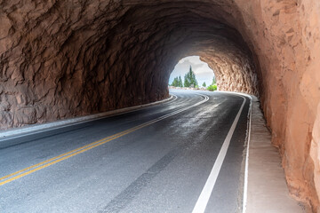 A two lane automobile tunnel cut into sandstone with a bend to the left, Colorado National...