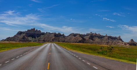Highway heading towards badlands rock formation on a beautiful day