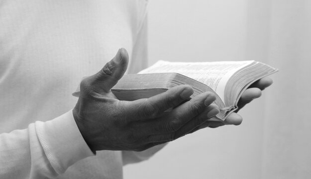 praying to god with hands together Caribbean man praying with grey black background stock image stock photo