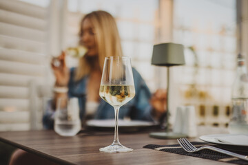 Wine glass on  a restaurant table with a woman in the background - 630877323