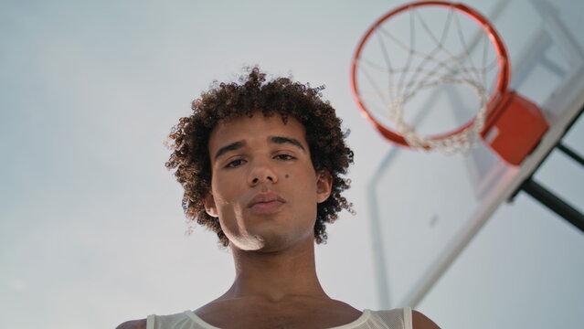 Basketball player posing street portrait. Man looking camera with orange ball