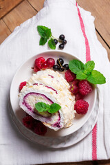 Meringue roll with whipped cream and currant curd, served with berries on a ceramic plate. Rustic style.