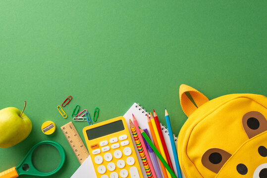 Elementary school education concept. Top view photo of colorful school supplies with yellow kid's school bag on green chalkboard isolated background with copy-space for text or advertising