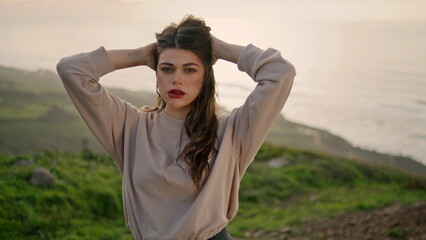 Beautiful girl posing hill seashore with ocean backdrop close up. Stylish model.