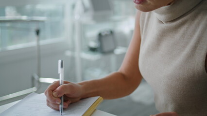 Elegant woman writing papers sitting at cabinet on skincare procedures closeup.