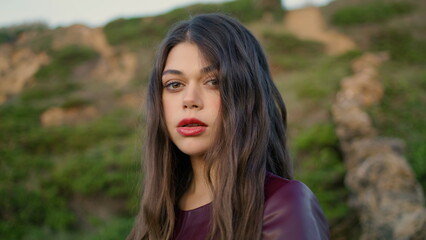 Naklejka premium Portrait gentle young brunette in front green hill. Woman posing gloomy weather.