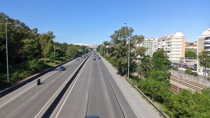 A long, wide expressway that runs between the park and the city of Lisbon