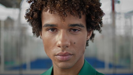 Serious teen staring lens outdoors closeup. Calm macho man face looking camera