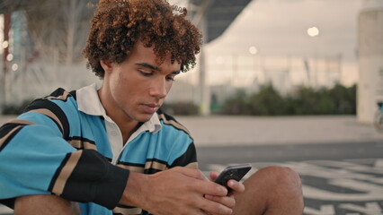 Focused hipster texting smartphone evening city. Teen use mobile phone closeup