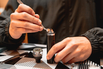 Technician using tweezers to accommodate the vape pen cotton.