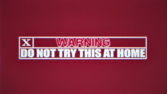 A VHS tape playing a simple warning text message, Do not try this at home. Dark red background.
