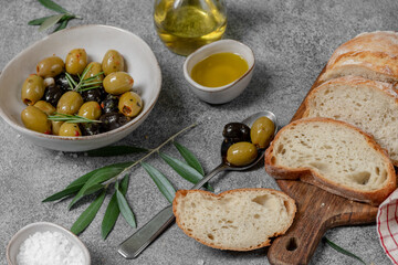 green and black olives in olive oil with herbs and  ciabatta bread