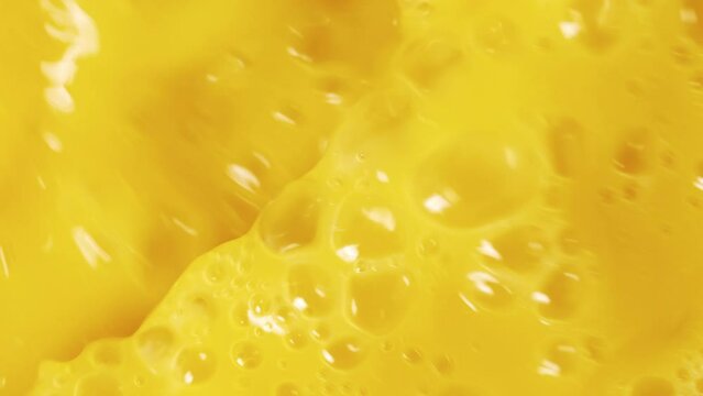 Close-up fresh orange juice mixing flowing and splashing slow motion shot, tropical fruit juice mix and splash being poured into large container