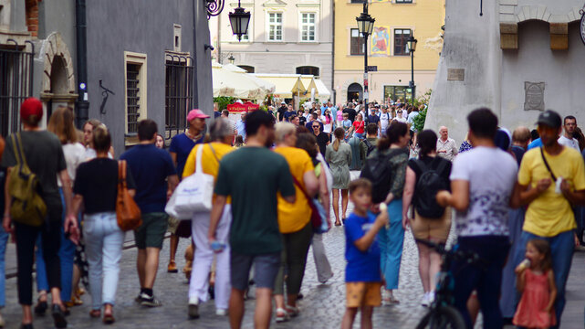 Warsaw, Poland. 29 July 2023. Crowd of people walking on a street. A crowd moving against a background of an urban old city landscape.