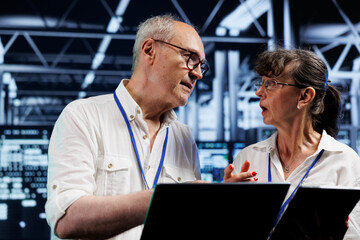 Aged technical support consultants in high tech establishment using tablet to set up configuration management tools that enable automatic failover and load balancing, preventing server errors