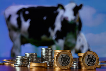 pile of coins in the form of a bar chart, in the background a picture of grazing cattle
